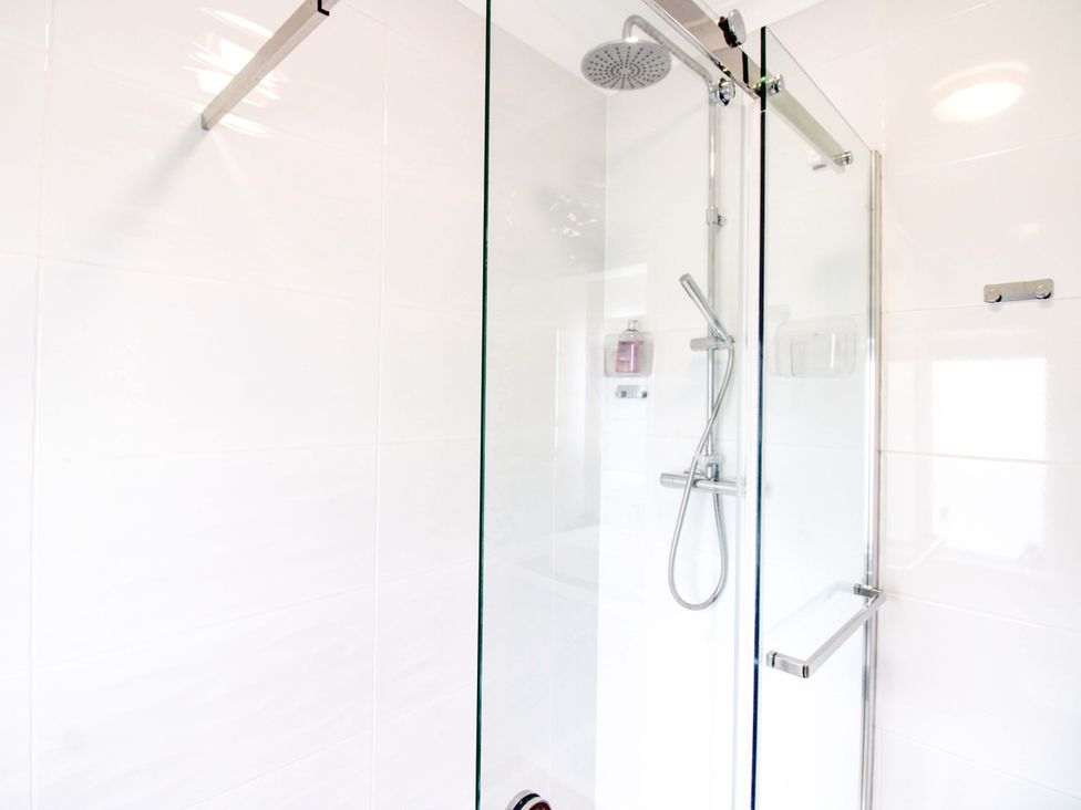 A shower with glass door and tiled wall at 4 The Elms Salcombe