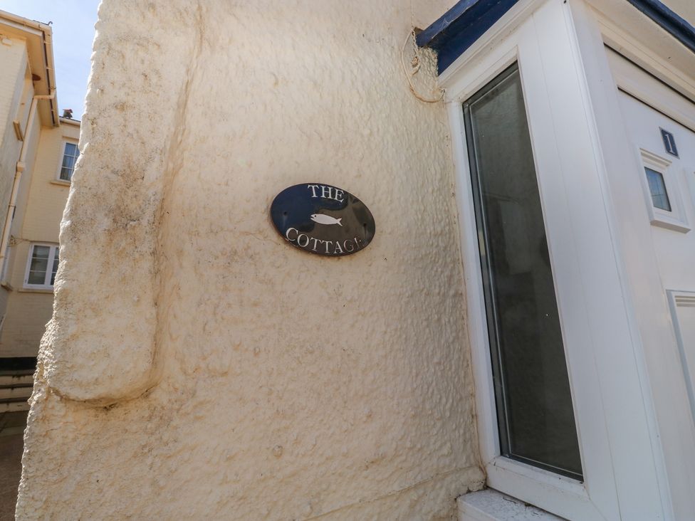 A nameplate on the wall next to a door at The Cottage in Budleigh Salterton