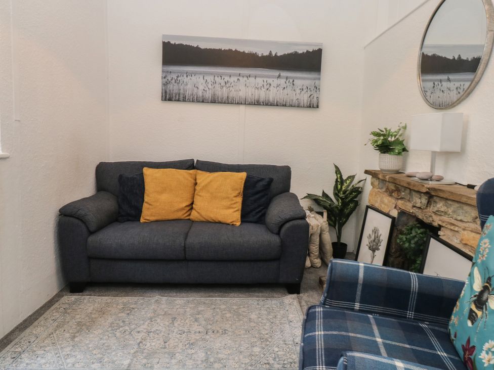 A snug with a gray sofa and yellow cushions at The Cottage Budleigh Salterton