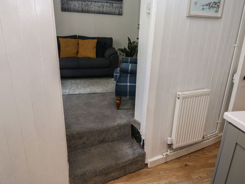A living room with stairs leading up and a sofa with cushions at The Cottage Budleigh Salterton