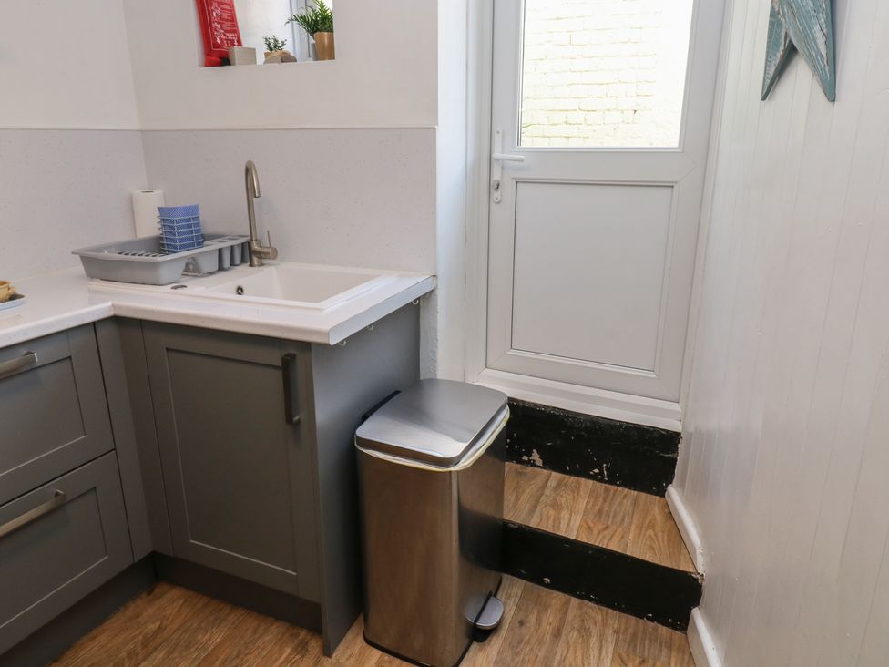 A kitchen with a sink and trash can at The Cottage in Budleigh Salterton