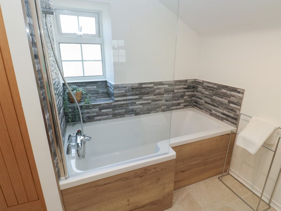 A bathroom with a bathtub and a towel rack at The Cottage Budleigh Salterton