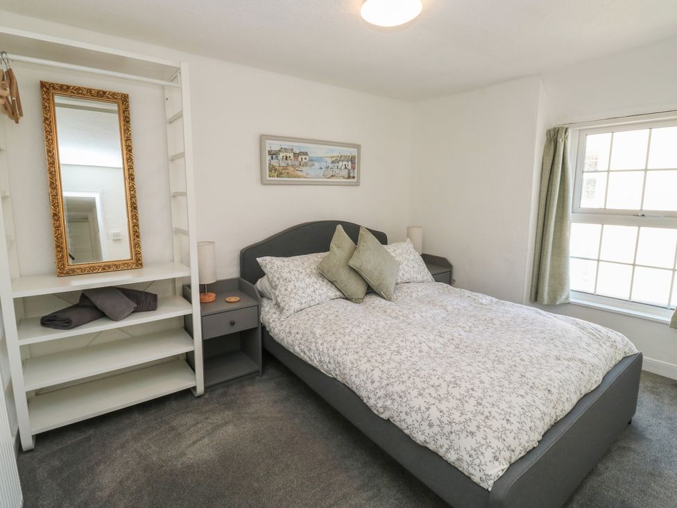 A bedroom with a bed and shelves at The Cottage in Budleigh Salterton