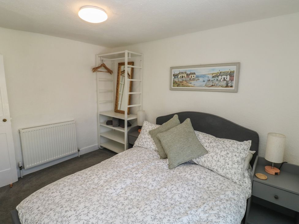 A bedroom with a bed and shelves at The Cottage in Budleigh Salterton