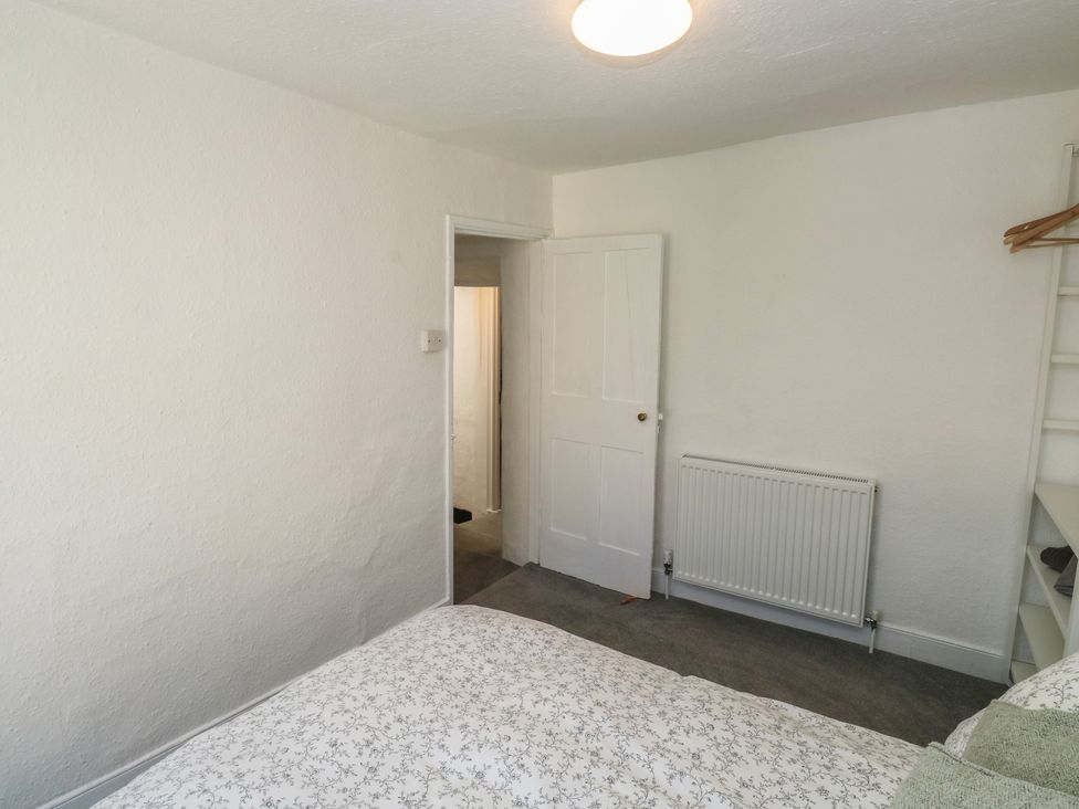 A bedroom with a bed and door leading to another room at The Cottage in Budleigh Salterton