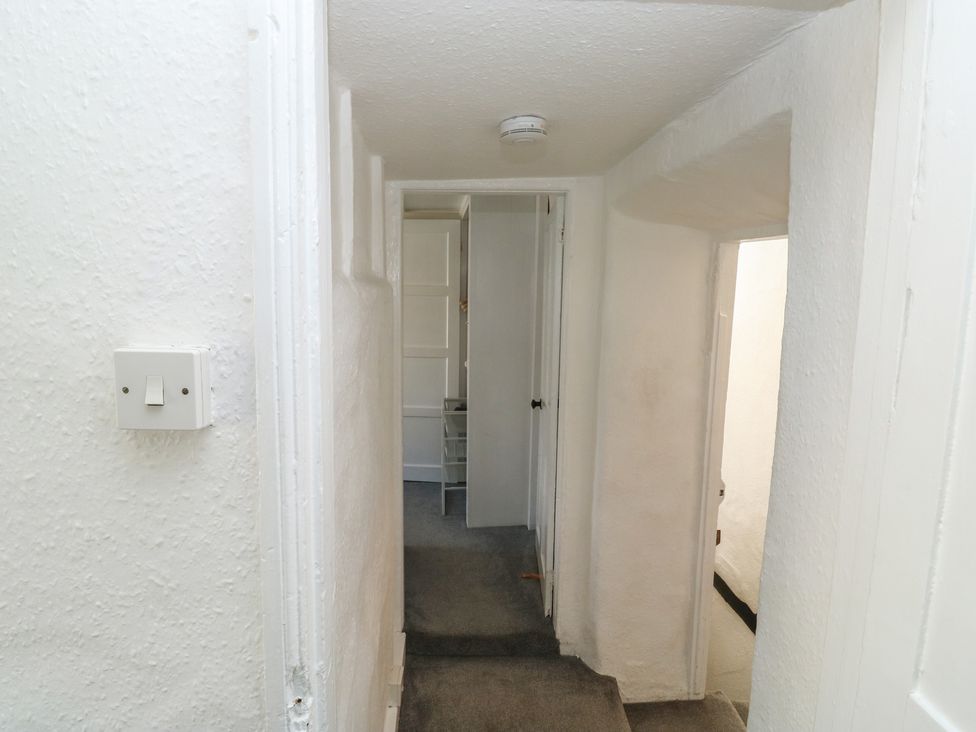 A hallway with a light switch and doors at The Cottage in Budleigh Salterton