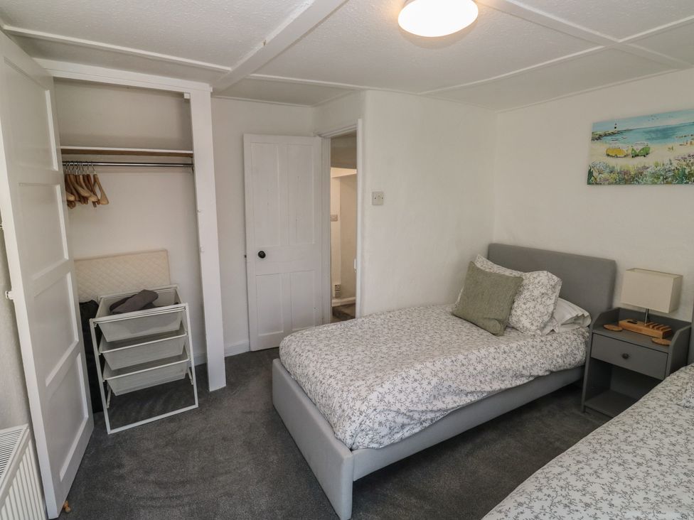 A bedroom with two beds and a wardrobe at The Cottage in Budleigh Salterton