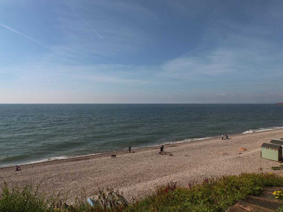 A beach with people walking and a beach hut at The Cottage Budleigh Salterton