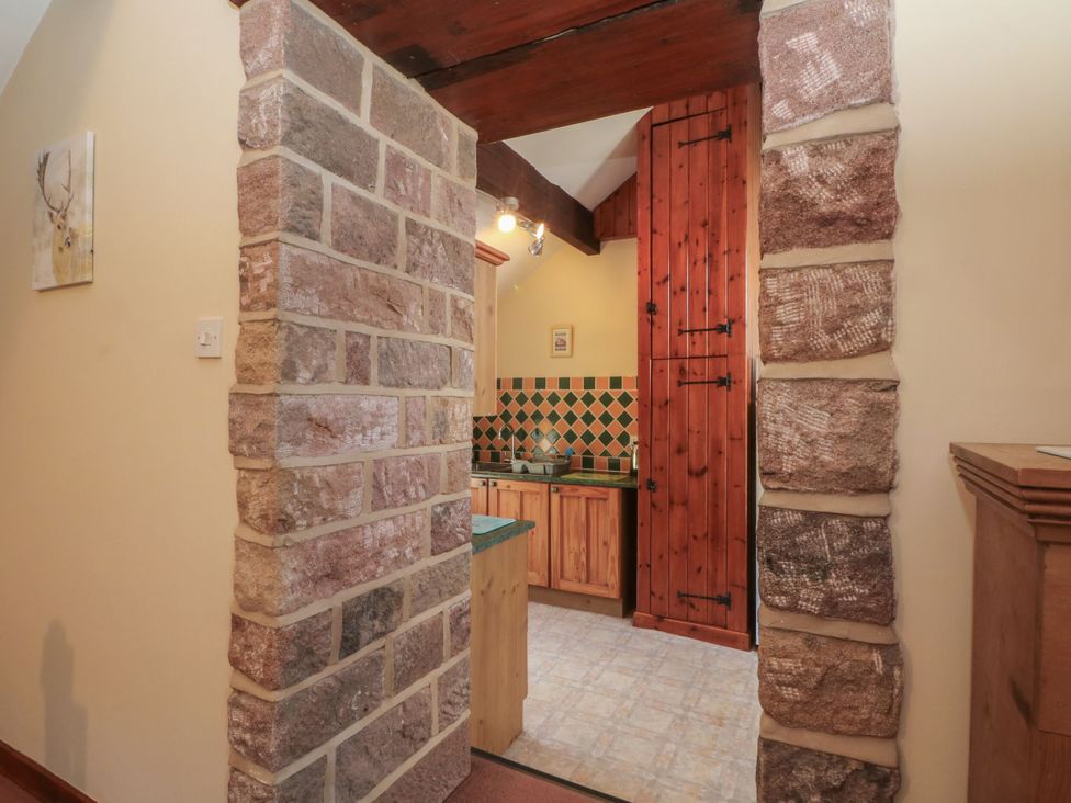 A kitchen with stone walls and wooden cabinets at Pearls Farm One in Wildboarclough near Macclesfield