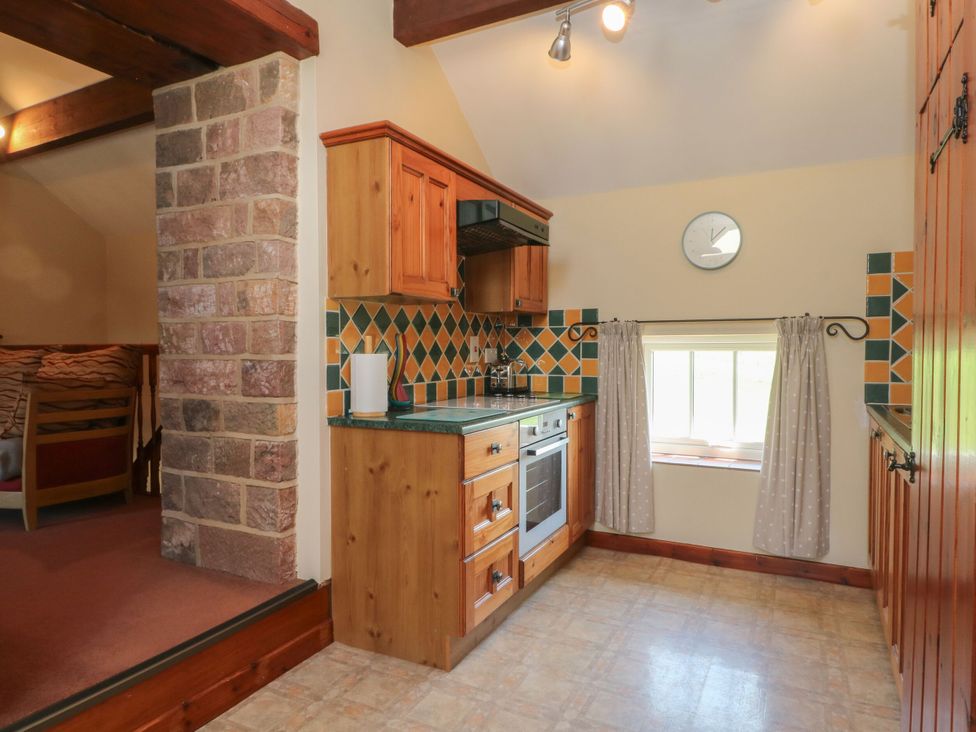 A kitchen with wooden cabinets and a window at Pearls Farm One Wildboarclough near Macclesfield