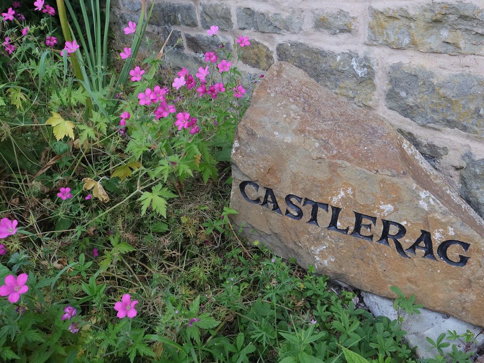 A stone with the name Castlerag surrounded by flowers at Castlerag in Parkend