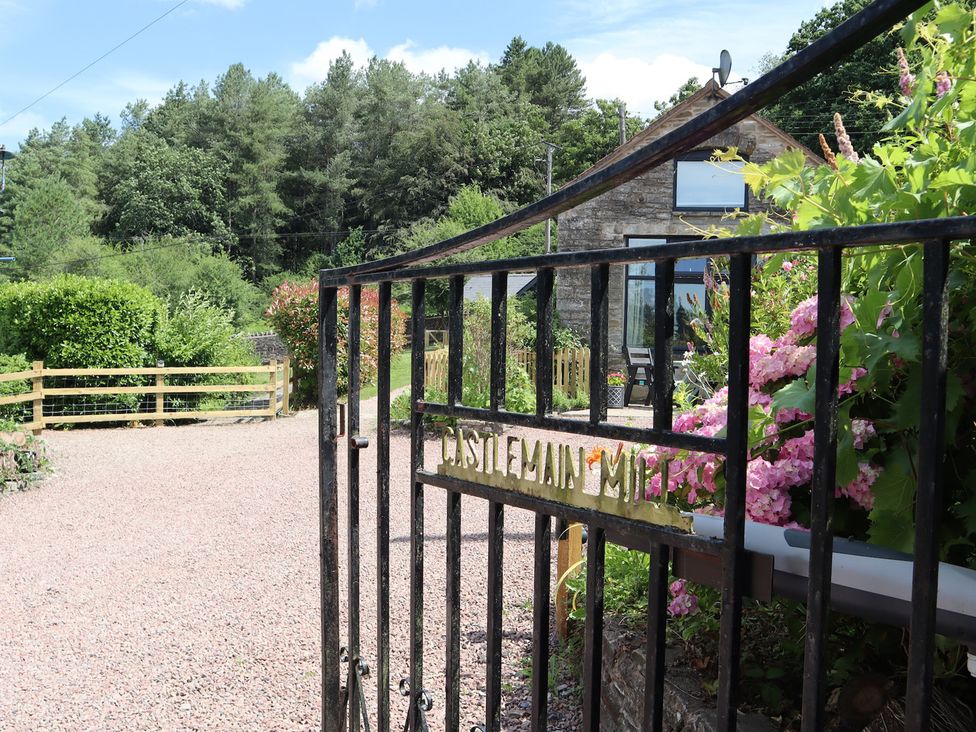 A view of a garden entrance with flowers and a gate at Castle Rag in Parkend