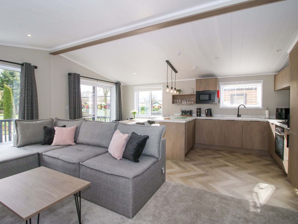 A living room with a sofa and kitchenette at Tulip in Eardisland