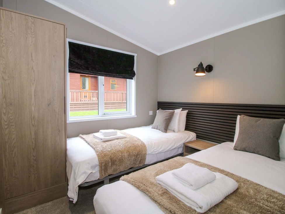 A bedroom with two beds and a wardrobe at Tulip in Eardisland