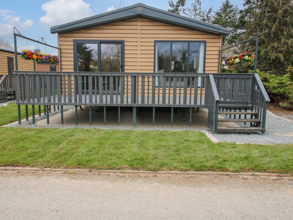 A wooden cabin with a deck and planters at Tulip in Eardisland