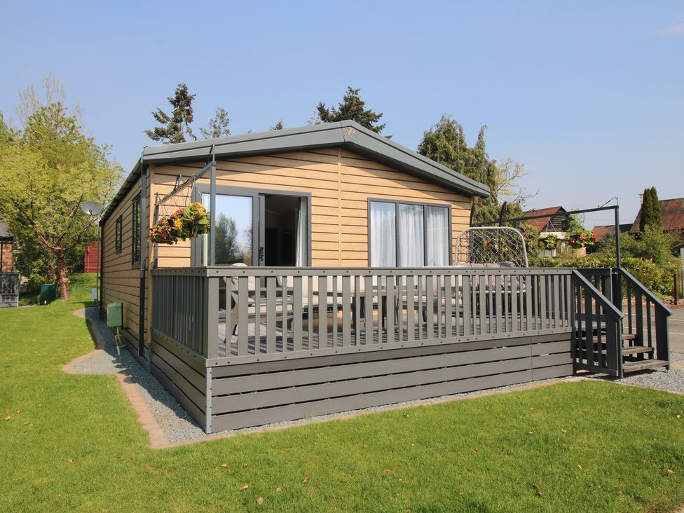 A wooden house with a deck and grassy area at Tulip in Eardisland