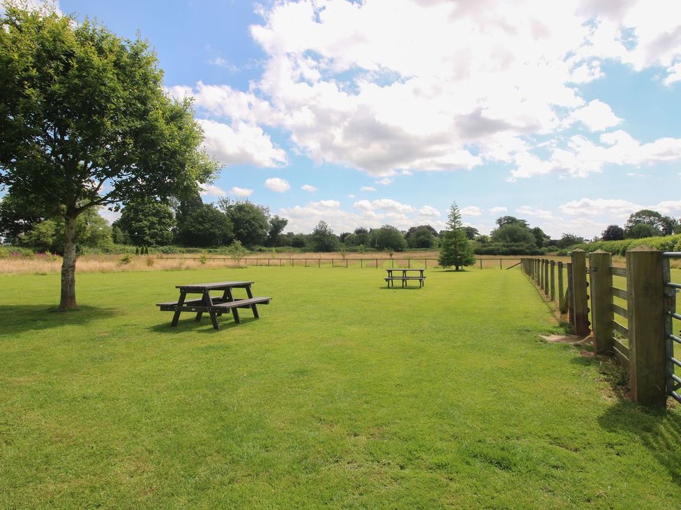 A grassy area with picnic tables and trees at Poppy in Eardisland