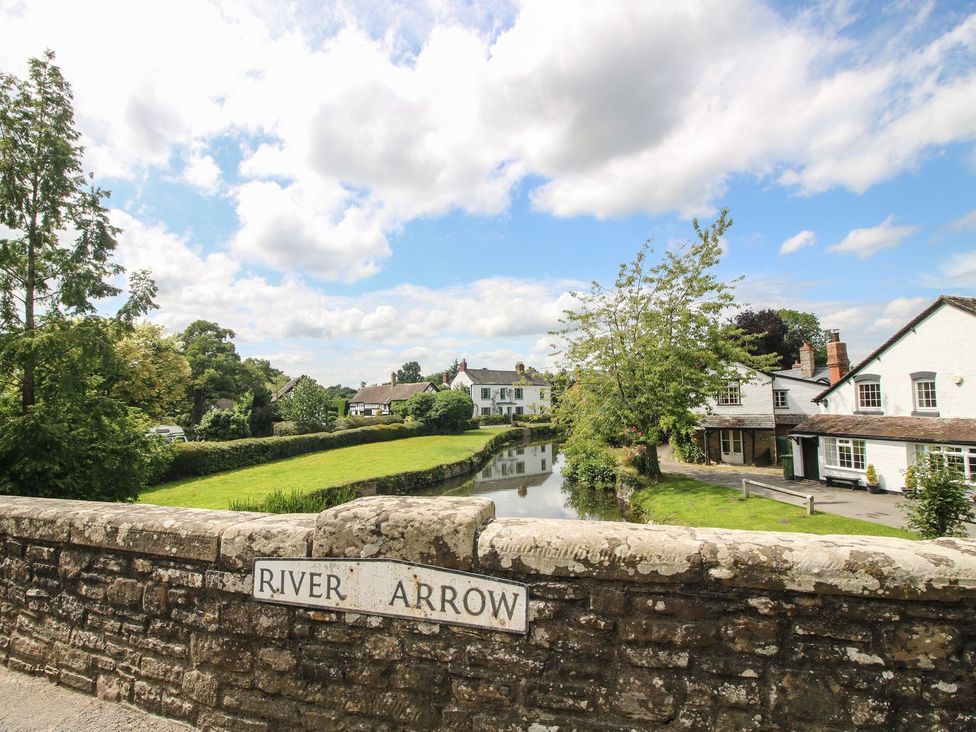 A view of the River Arrow with houses and trees at Poppy in Eardisland