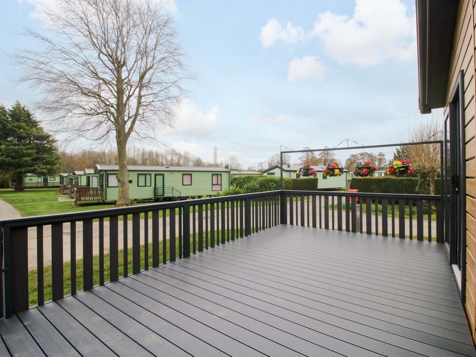 A deck area overlooking holiday homes and trees at Poppy Eardisland