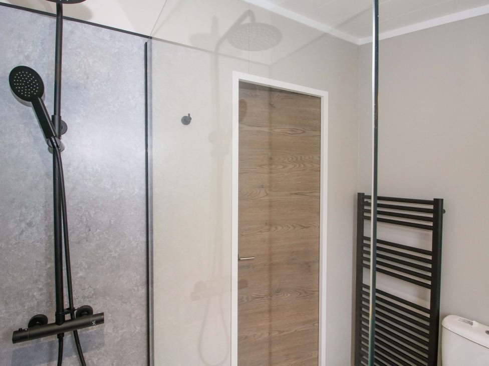 A bathroom with a shower, toilet, and towel radiator at Poppy in Eardisland