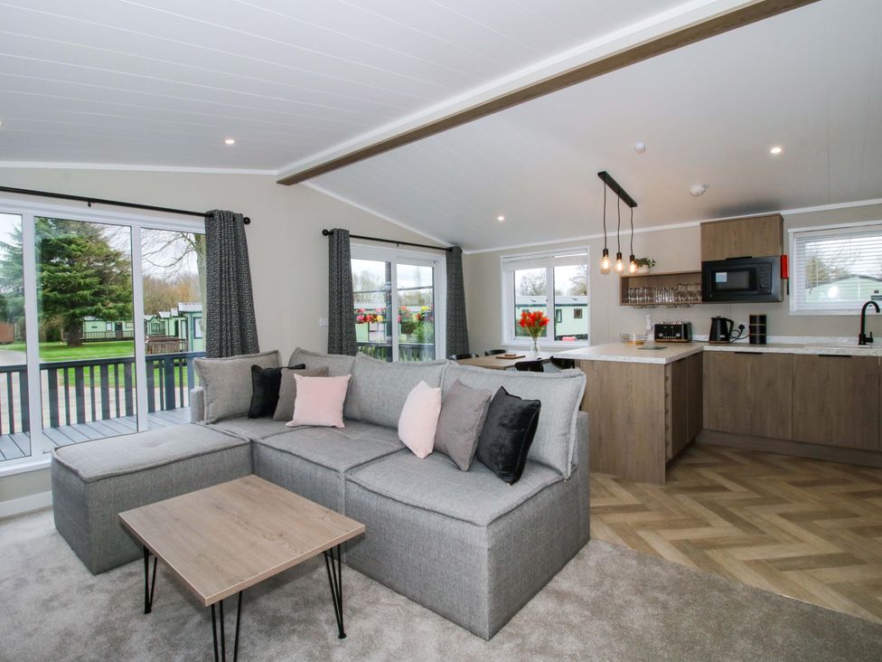 A living room with a sofa and kitchen area at Poppy in Eardisland