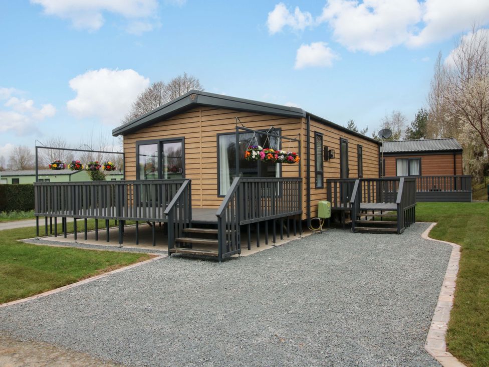 A mobile home with a deck and lawn at Poppy in Eardisland