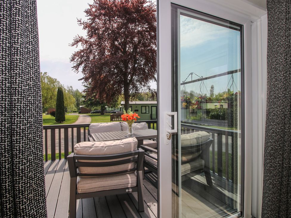 A deck with outdoor furniture overlooking a garden at Poppy in Eardisland
