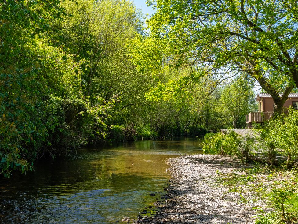 A river with trees and a building nearby at Poppy Eardisland