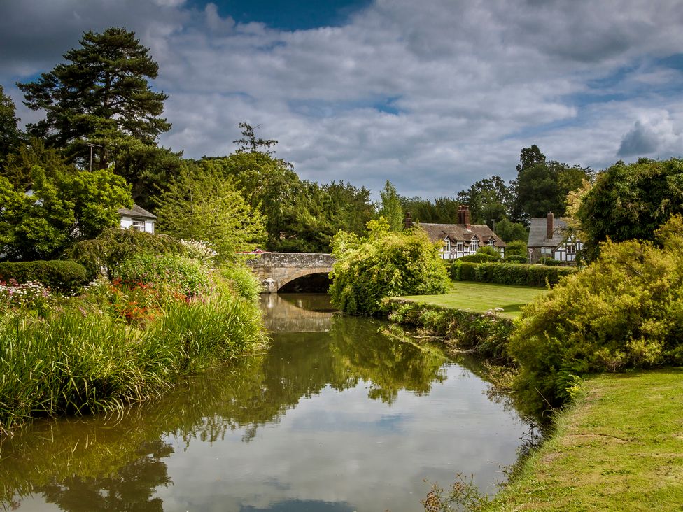 A view of a river with a bridge and houses in Eardisland