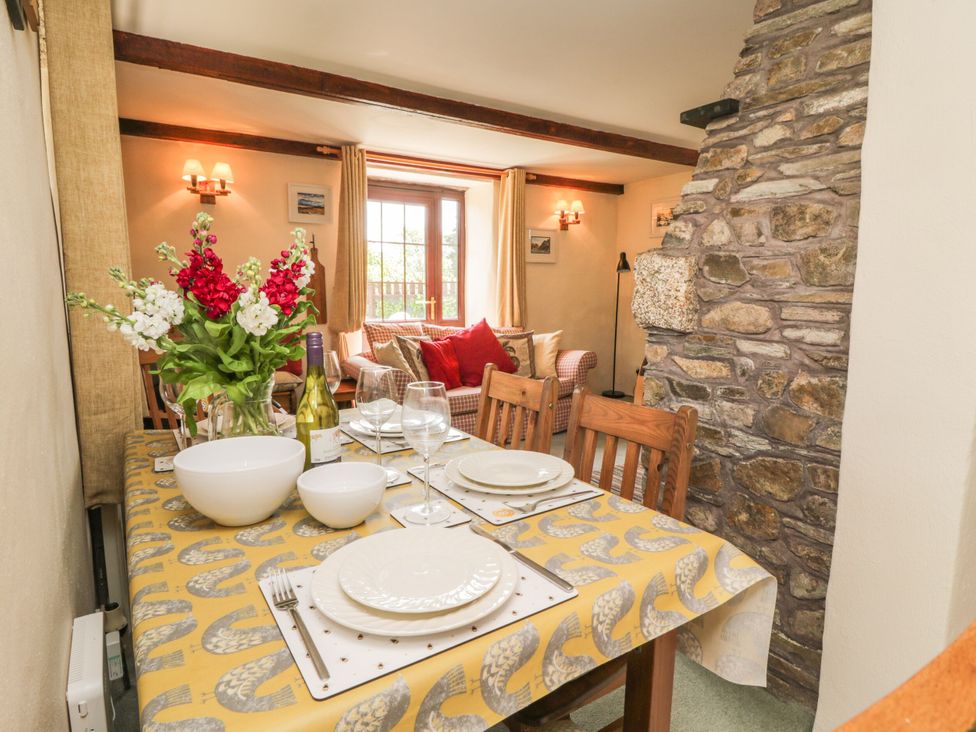 A dining table set with plates and flowers at Applestore in Wadebridge