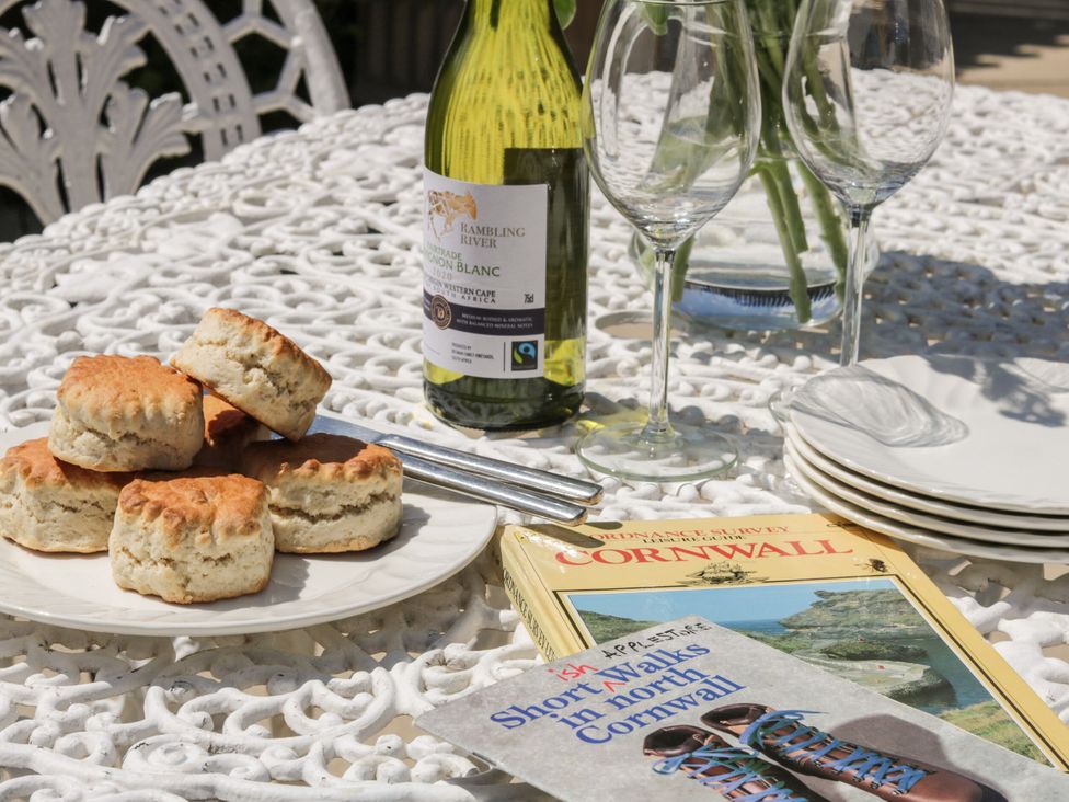 An outdoor dining area with scones, wine, and books at Applestore in Wadebridge