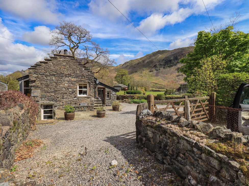 A stone house with trees and a gravel path at Beckside Studio Penrith
