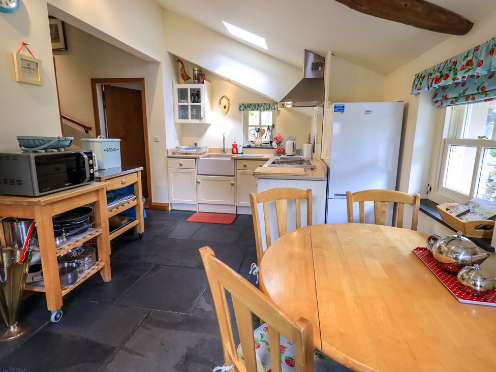 A kitchen with a microwave, sink, stove, and table at Beckside Studio in Penrith