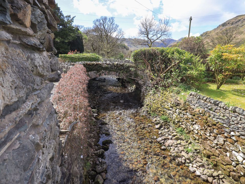 A stone bridge over a stream with stone walls and trees at Beckside Studio Penrith