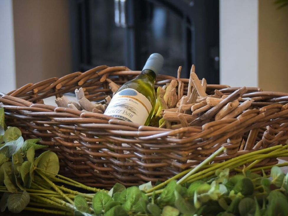 A basket containing a wine bottle and driftwood at Juniper Cottage