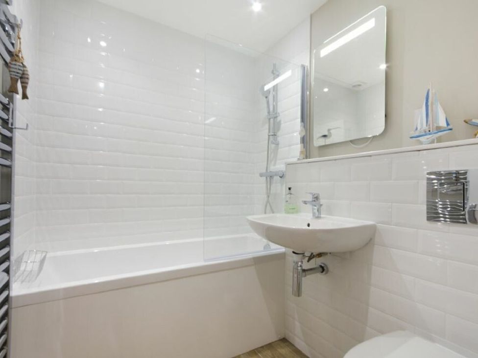A bathroom with a bathtub, sink, and shower at Juniper Cottage