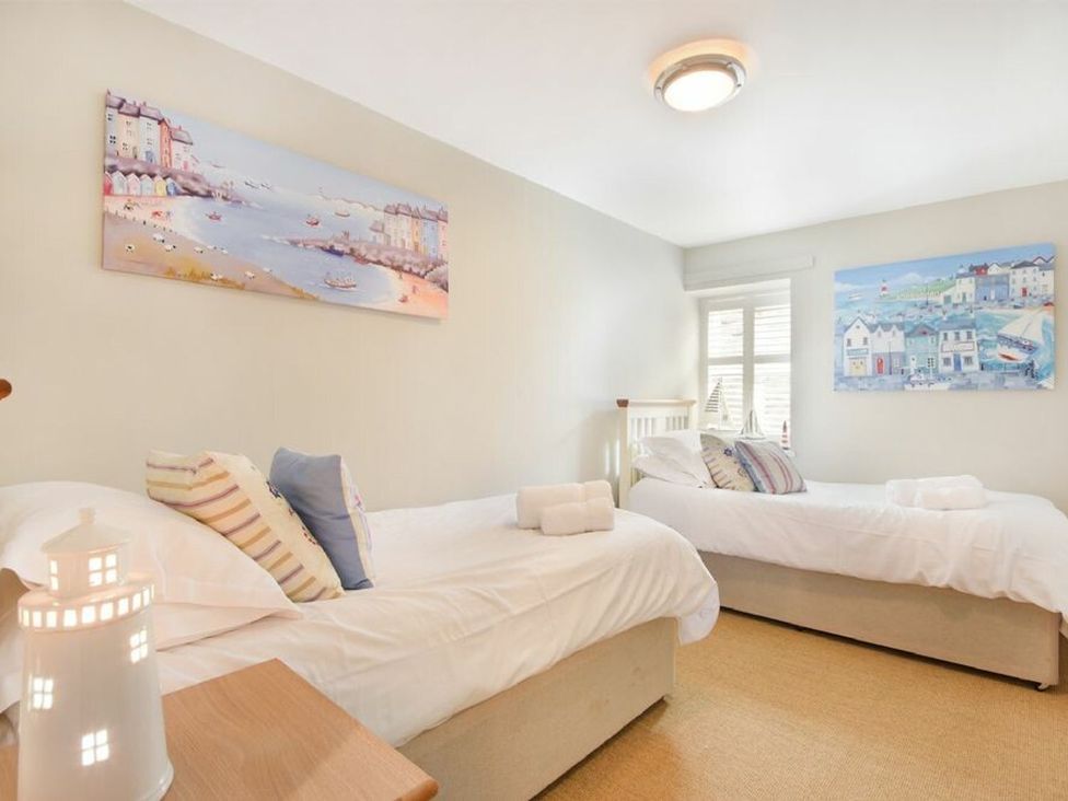 A bedroom with two beds and paintings on the wall at Juniper Cottage