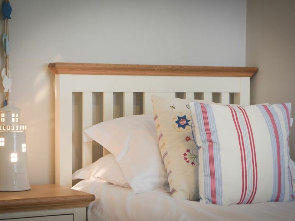 A bed with pillows and a lamp at Juniper Cottage
