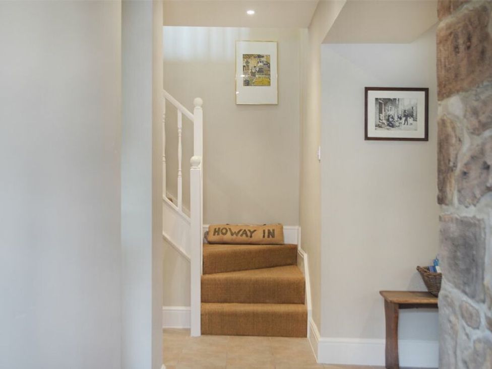 A hallway with stairs and framed pictures at Juniper Cottage
