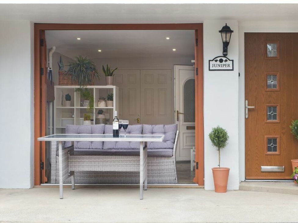 An outdoor seating area with a couch, table, and plants at Juniper Cottage