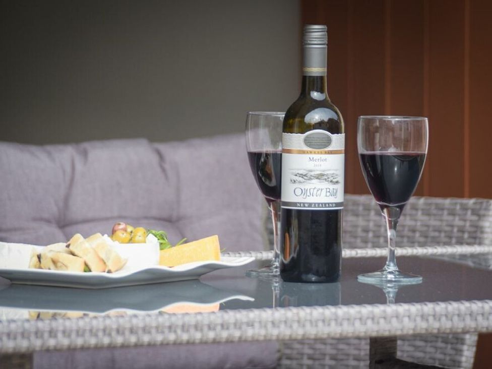 A wine bottle and glasses with cheese and bread on a platter at Juniper Cottage 