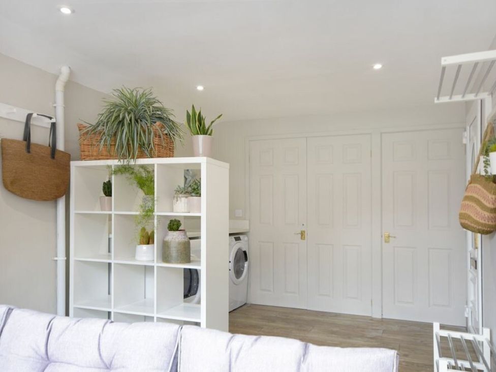 A utility room with shelves and a washing machine at Juniper Cottage