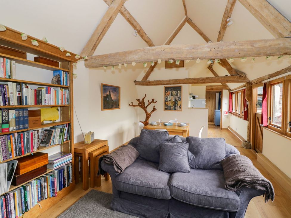 A living room with a sofa, bookshelf, and dining area at Ryepiece in Stratford-upon-Avon