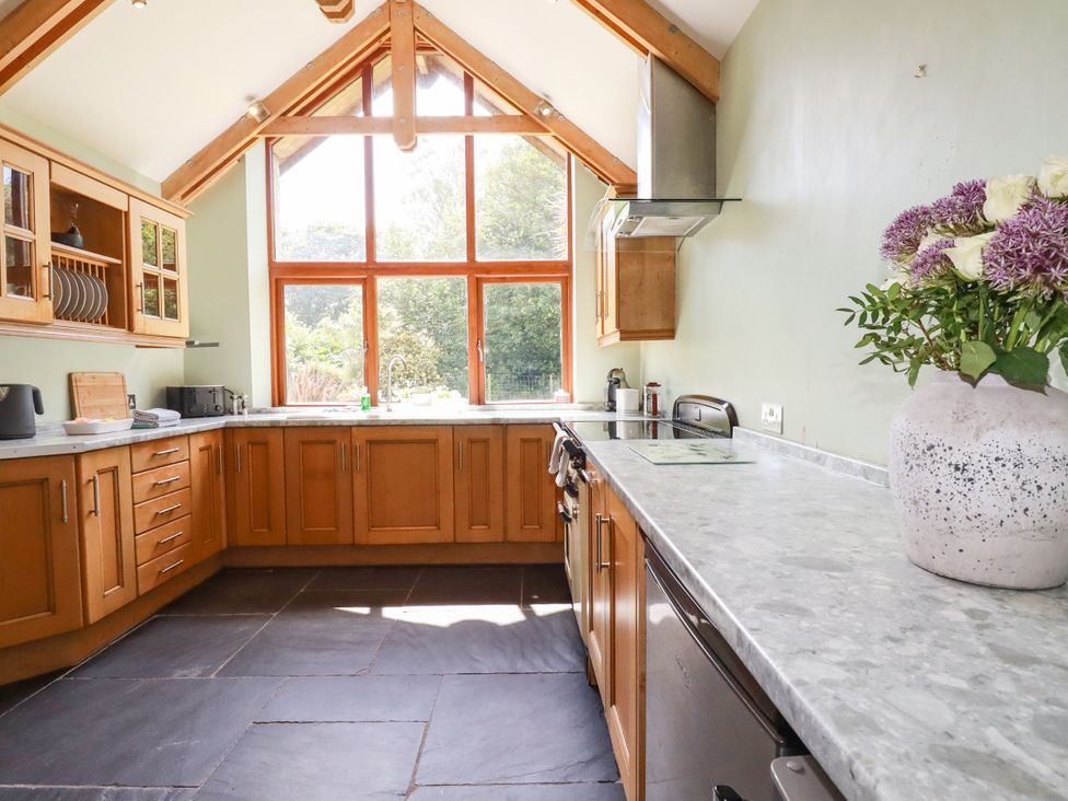 A kitchen with wooden cabinets and a marble countertop at Little Trethellan near Lanner