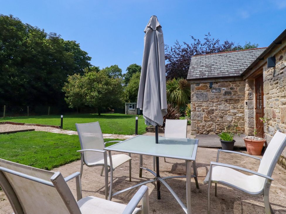 An outdoor seating area with a table and chairs at Little Trethellan in Trethellan near Lanner