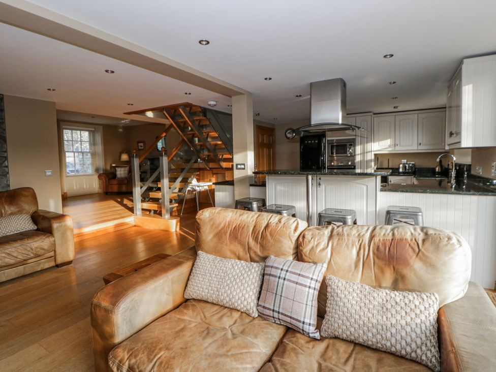 A living room with a sofa and staircase at Awelon Y Mor Aberaeron