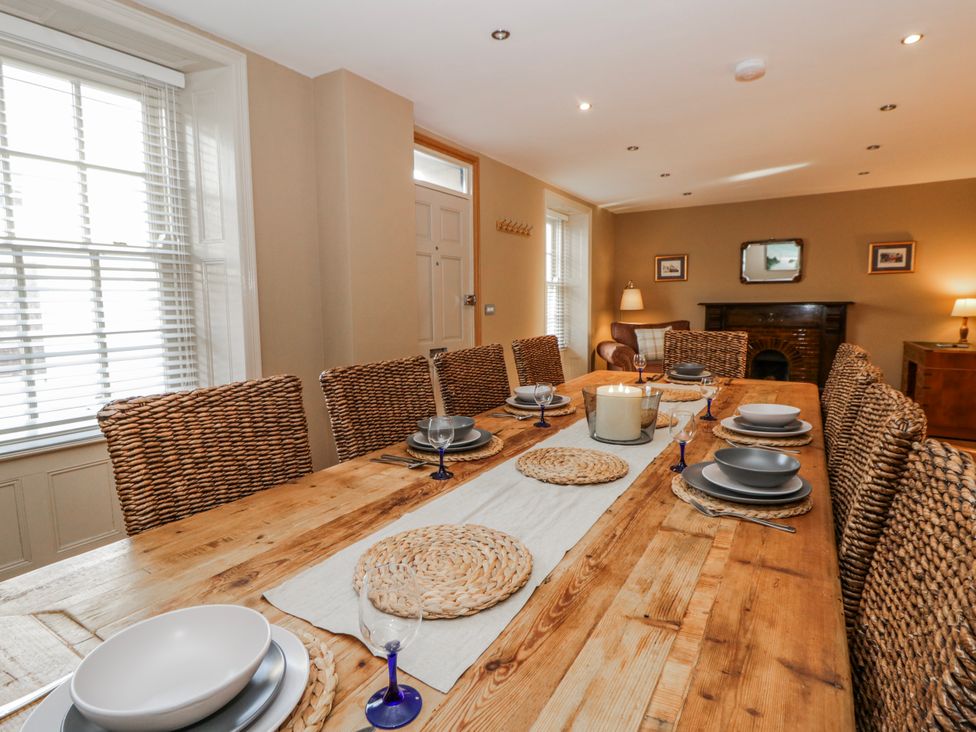 A dining room with a wooden table and wicker chairs at Awelon Y Mor in Aberaeron