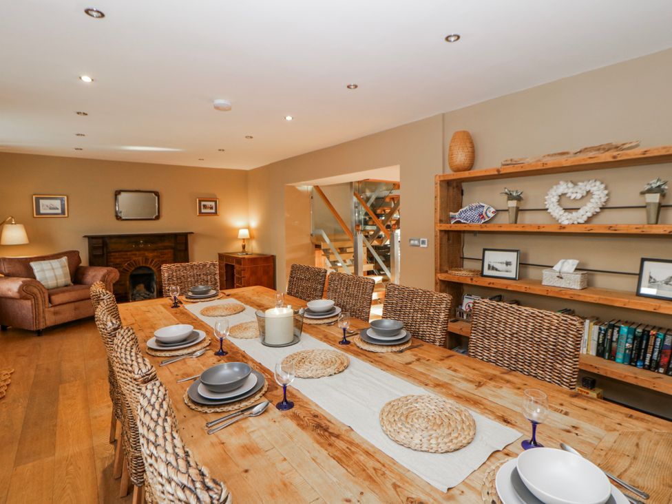 A dining room with a large wooden table and chairs at Awelon Y Mor Aberaeron