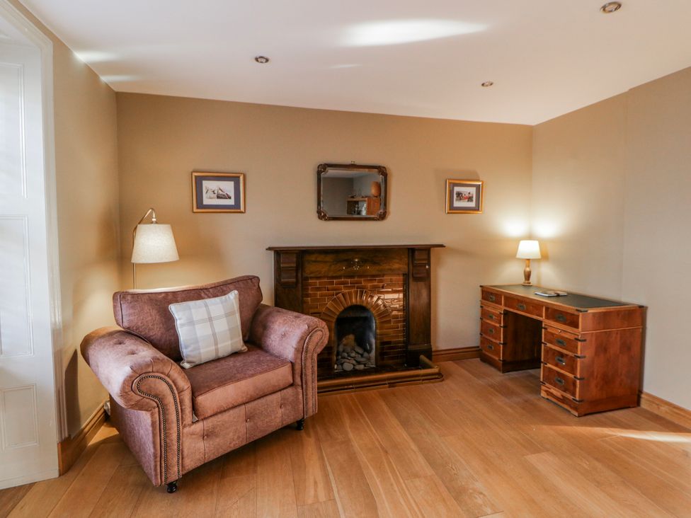 A living room with an armchair and fireplace at Awelon Y Mor in Aberaeron
