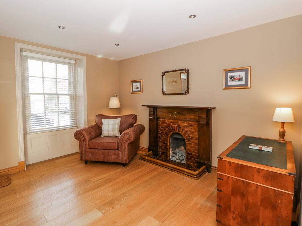 A living room with a fireplace and armchair at Awelon Y Mor in Aberaeron